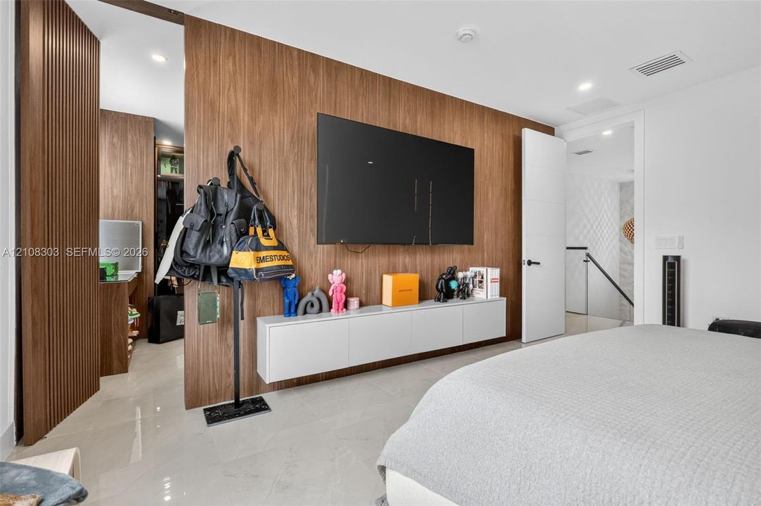 Custom wood-panel accent wall featuring a wall-mounted matte white floating credenza, recessed lighting, and large-format tile flooring