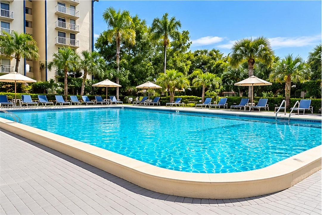 Swimming pool with a stone paver deck, palm tree landscaping, and metal pool entry rails