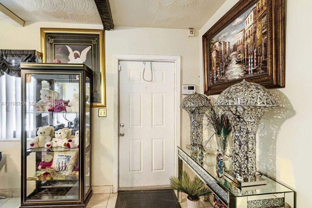 Entryway featuring a four-panel door with metallic hardware, textured ceiling, and light-colored tile flooring