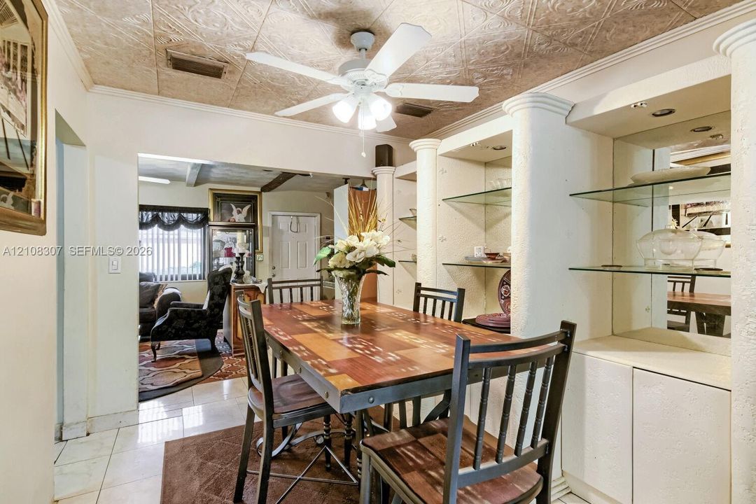 Textured ceiling with decorative pattern, integrated shelving units with glass display tiers, mirrored back panels, and structural columns