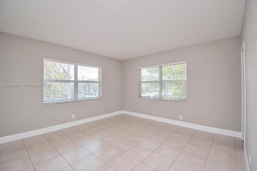 Neutral-toned interior featuring large windows, light-colored tile flooring, and a textured ceiling finish