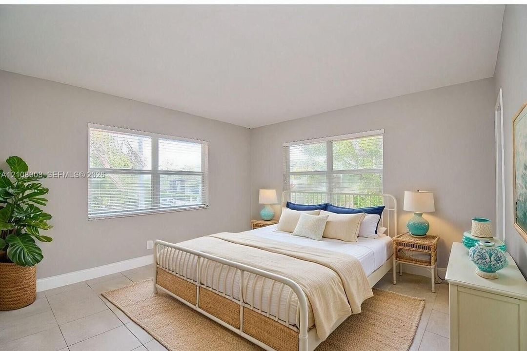 Neutral-toned interior space featuring light-colored tile flooring, expansive multi-pane windows, and high-reaching ceilings