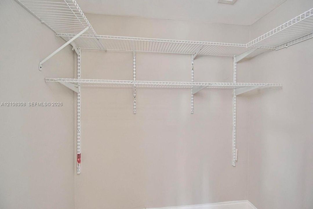 Wall-mounted white wire shelving system featuring tiered storage levels and adjustable support tracks