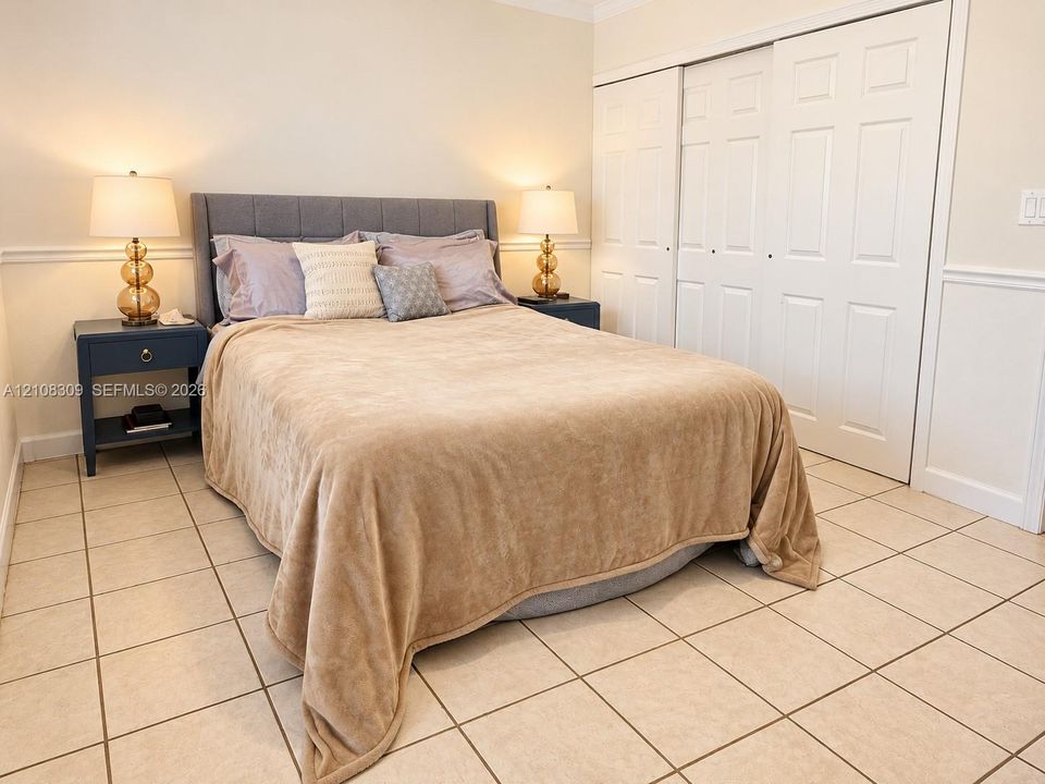 Ceramic tile flooring, white six-panel sliding closet doors, and chair rail molding