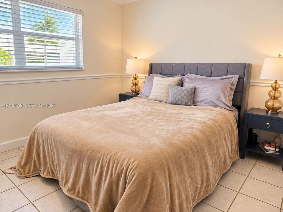 Neutral wall-to-wall ceramic tile flooring, horizontal window blinds, and decorative chair rail molding