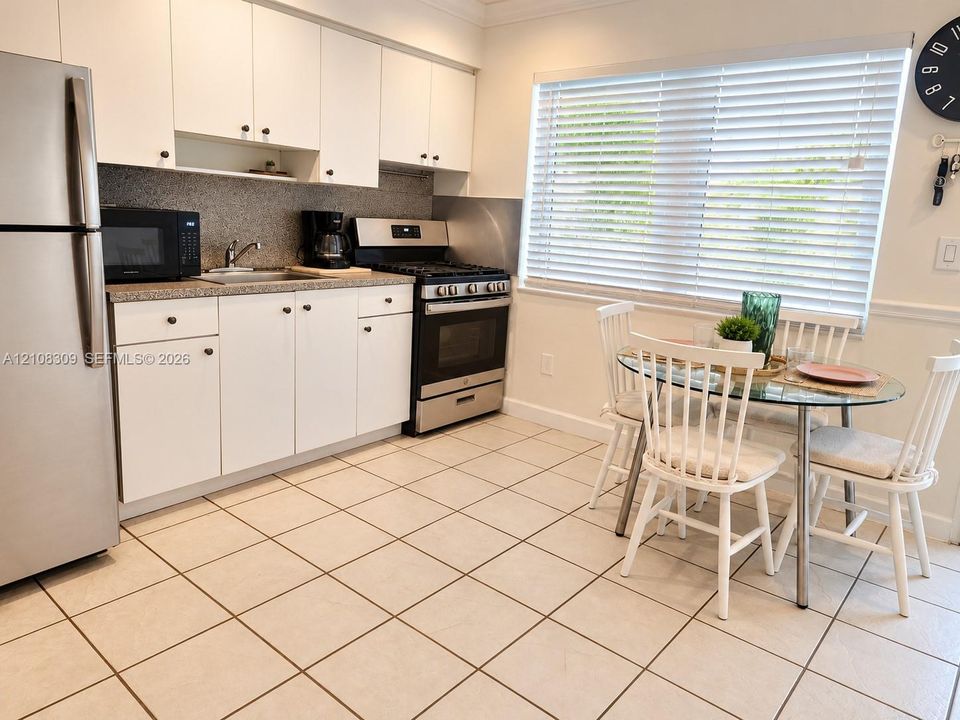 Kitchen featuring white cabinetry, stone-finish countertops, stainless steel appliances, and tile flooring