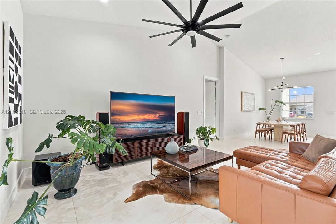 Vaulted ceilings, expansive tile flooring, and a contemporary matte black multi-blade ceiling fan