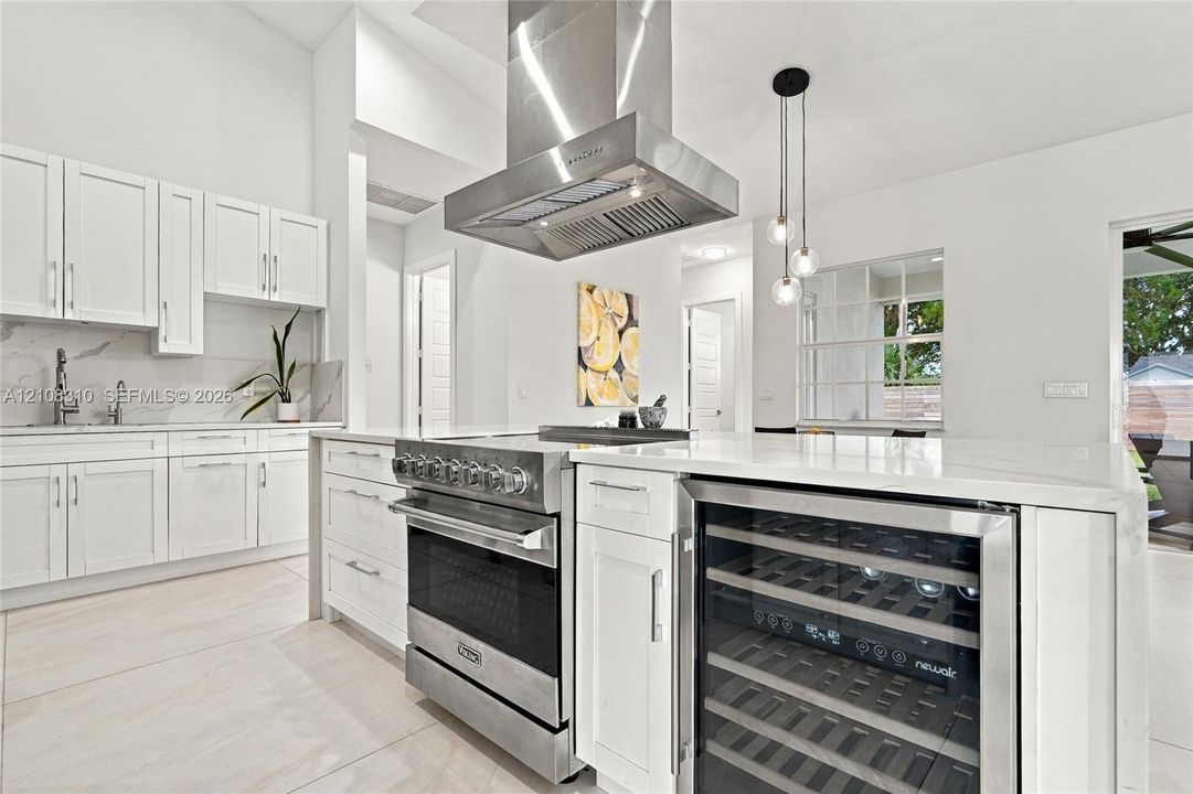 Kitchen featuring white cabinetry, stone-surface countertops, professional-grade stainless steel range, ceiling-mounted stainless steel vent hood, and built-in wine refrigerator
