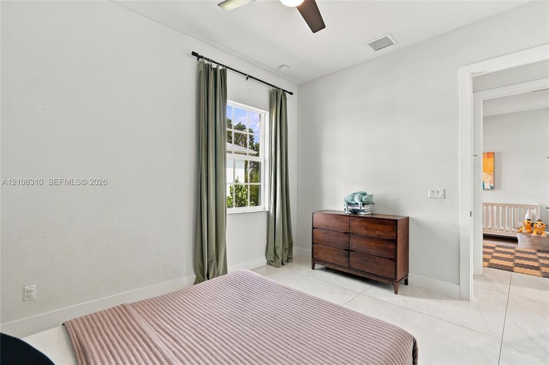 Neutral-toned room featuring large-format tile flooring, a multi-pane window, and a ceiling-mounted fan with integrated lighting