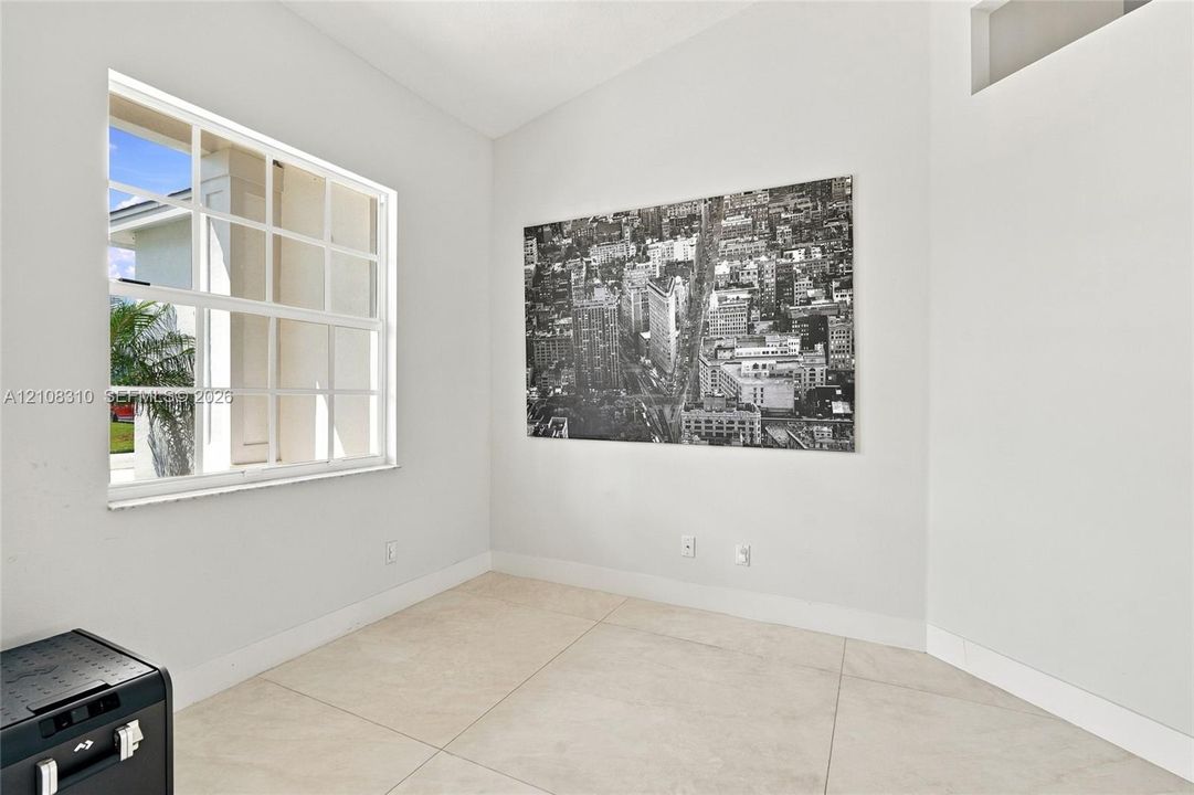 Vaulted ceiling, large multi-pane window, and light-toned tile flooring
