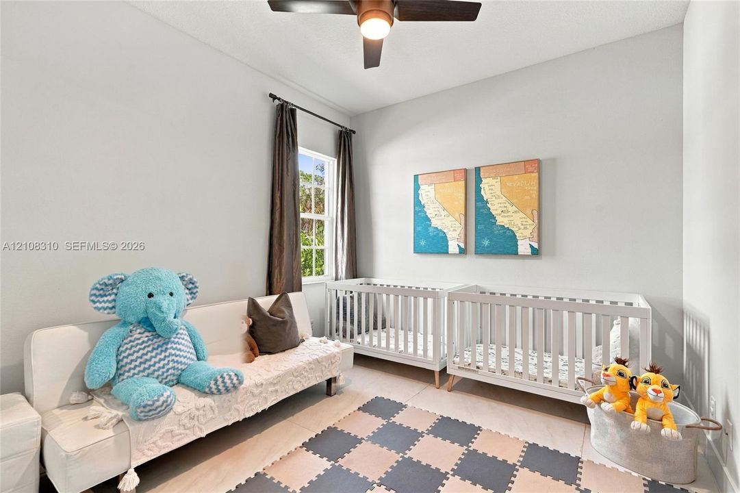 High-ceilinged room featuring neutral wall tones, large-format tile flooring, a multi-pane window, and a central ceiling fan with integrated lighting