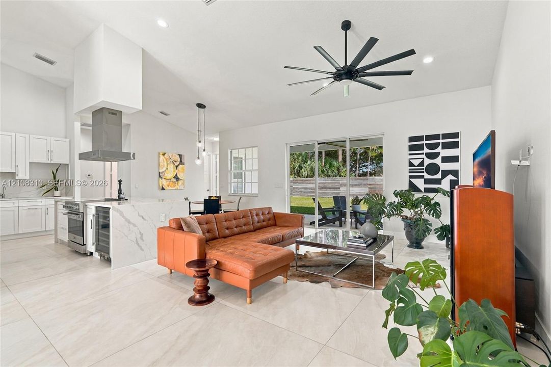 Open-concept floor plan featuring large-format tile flooring, vaulted ceilings, and a waterfall-edge kitchen island