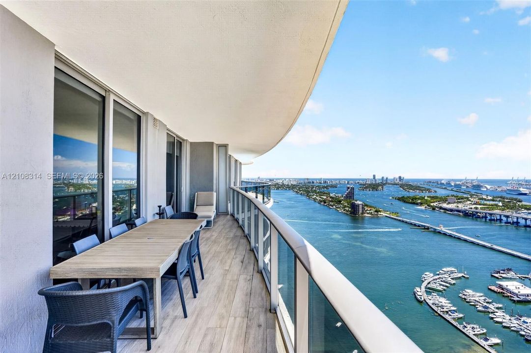 Expansive covered balcony featuring wood-finish tile flooring and a glass panel railing