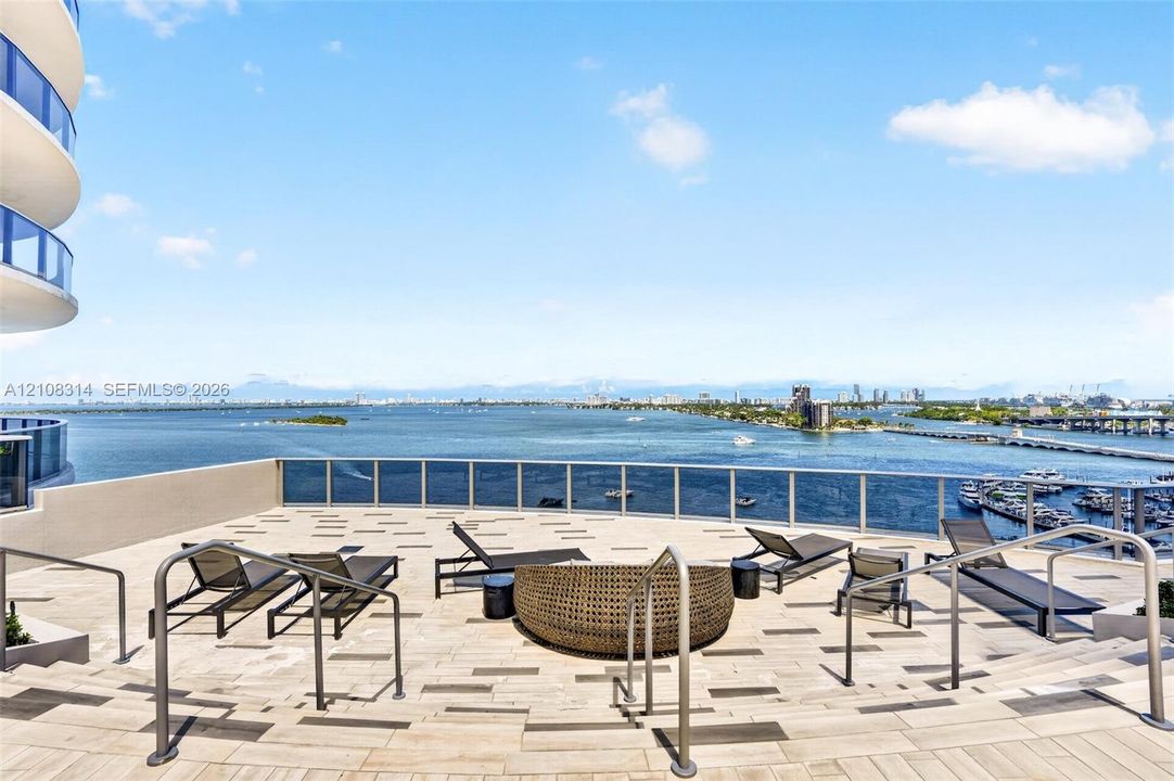 Expansive rooftop terrace featuring patterned stone-finish flooring, metal railing, and multi-level stepped access