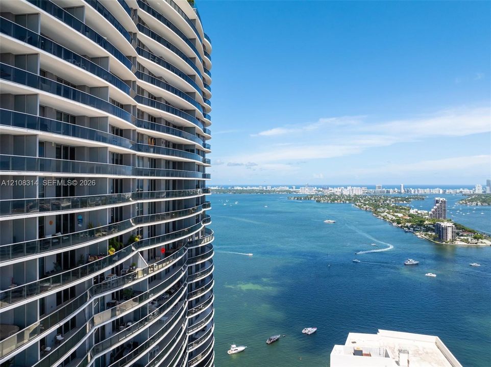 Curved high-rise exterior featuring floor-to-ceiling glass railings and tiered private balconies