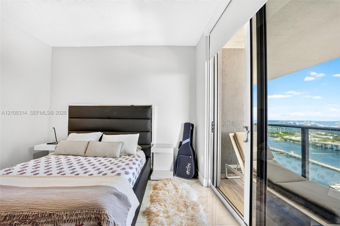 Floor-to-ceiling sliding glass door, private balcony with metal railing, and light-toned tile flooring