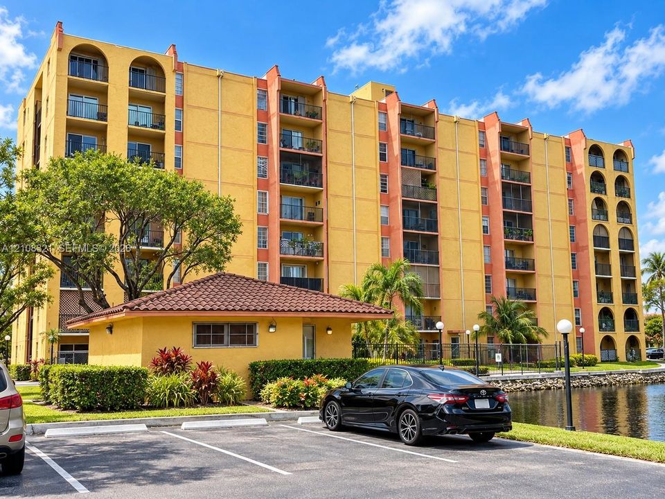 Multi-story residential building featuring arched balcony detailing, stucco exterior finish, attached private balconies, and waterfront landscaping