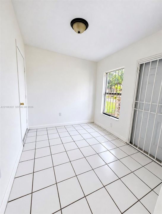 Interior space featuring white tile flooring, flush-mount ceiling lighting, and a metal security door