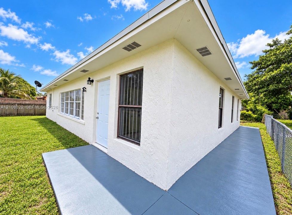 Exterior featuring a textured stucco finish, painted concrete patio, white door, multi-pane windows, and inset soffit lighting
