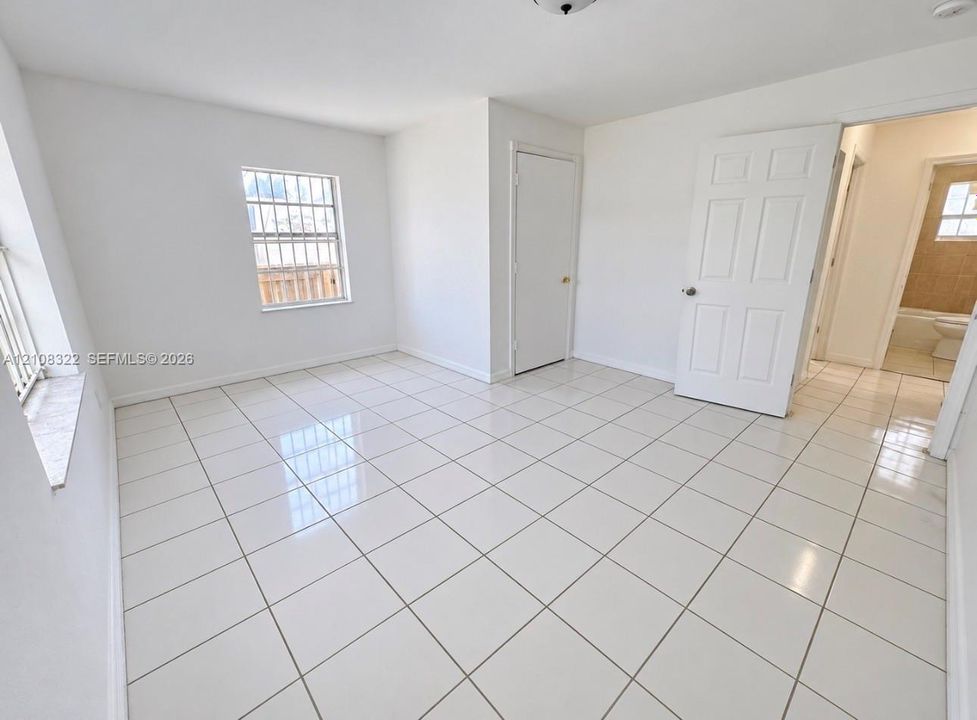 Neutral-toned interior space featuring polished tile flooring, white-painted walls, and six-panel interior doors