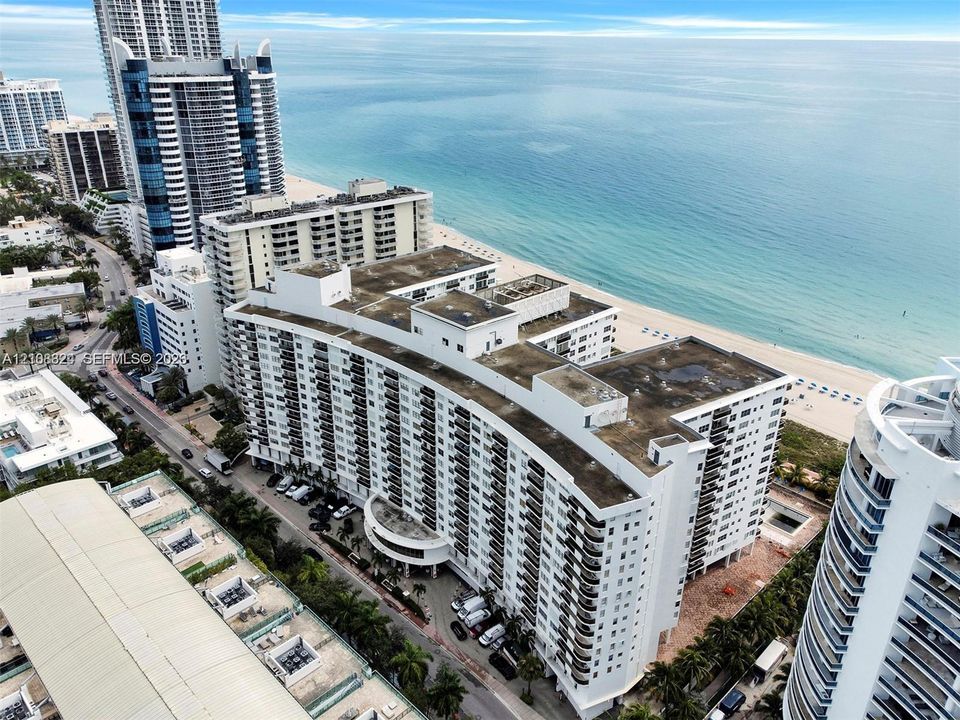 Mid-rise coastal residential building featuring a curved architectural design, private exterior balconies, and direct proximity to the oceanfront