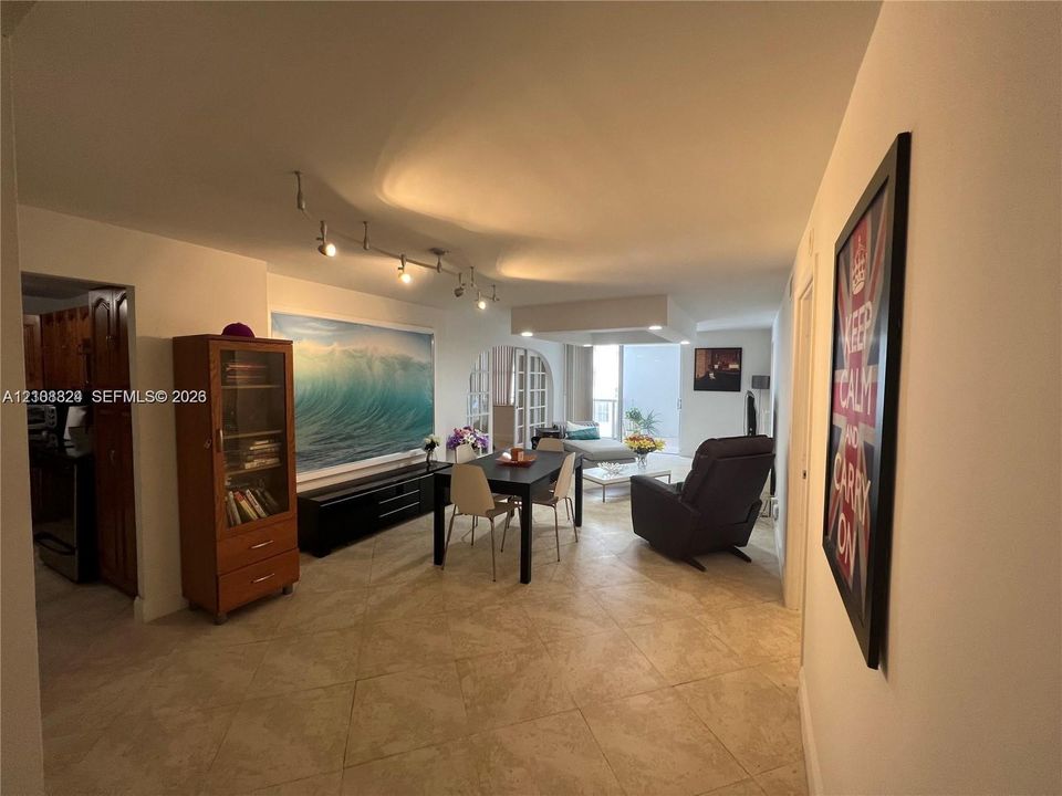 Large-format tile flooring, adjustable track lighting, and a distinct arched architectural doorway