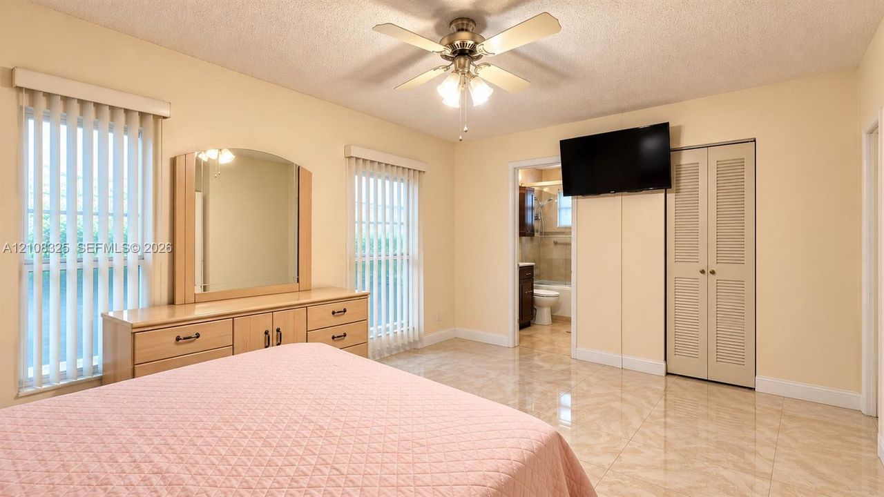 Room featuring ceramic tile flooring, dual windows with vertical blinds, a ceiling fan with integrated lighting, and a closet with louvered doors