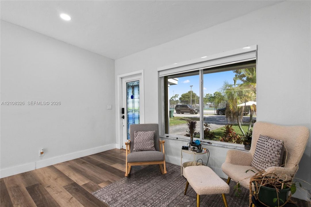 Wood-finish flooring, large picture window, and exterior door with decorative glass inlay and recessed lighting
