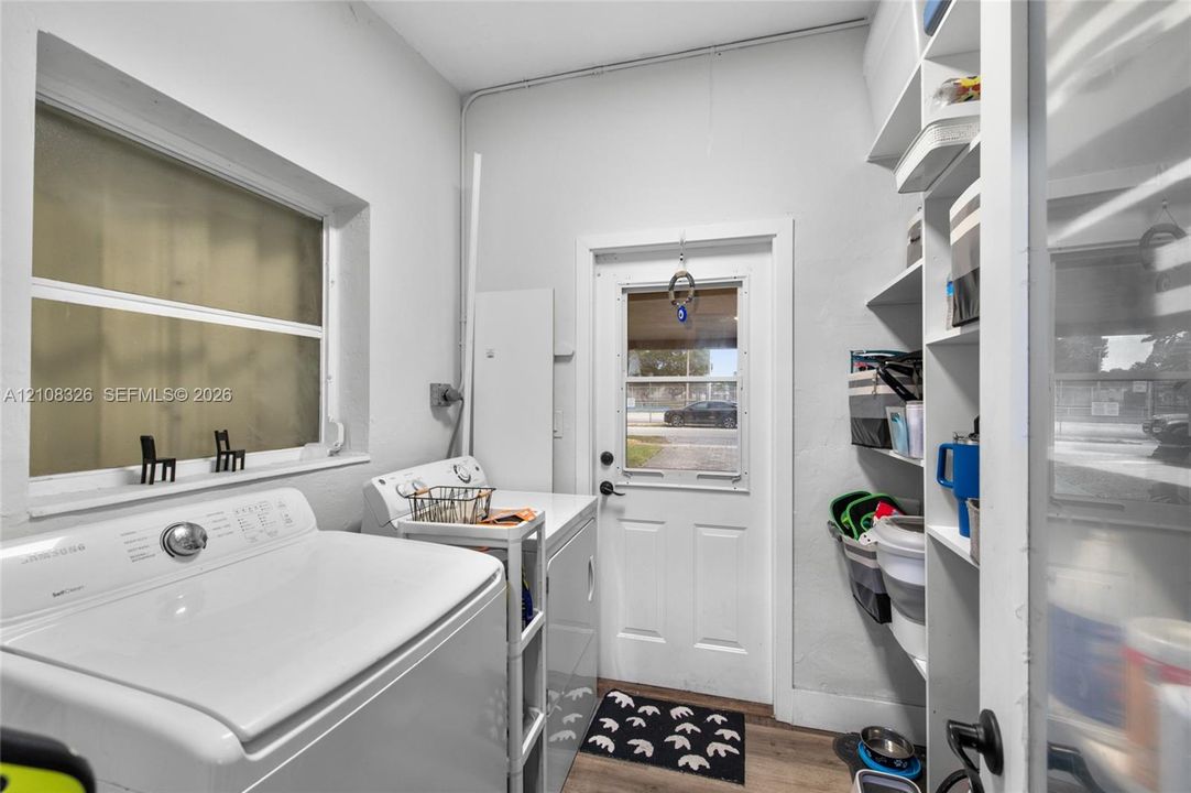 Laundry area featuring wood-finish flooring, white built-in shelving, and a glass-paneled exterior door
