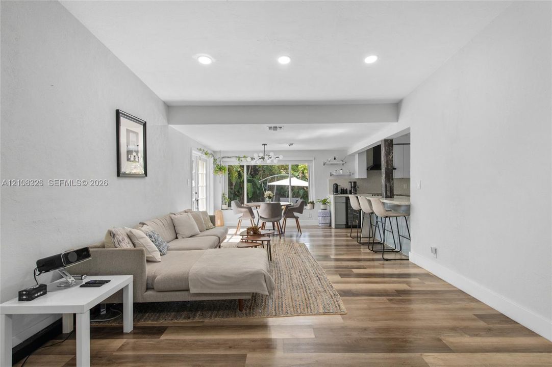 Open-concept interior featuring wood-finish flooring, recessed lighting, and a kitchen equipped with a breakfast bar