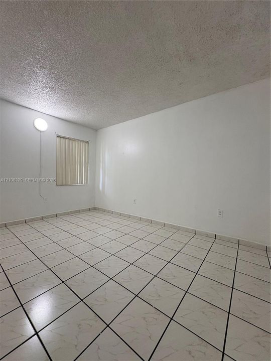 Interior space featuring neutral wall paint, square ceramic floor tiles, and a window with vertical blinds