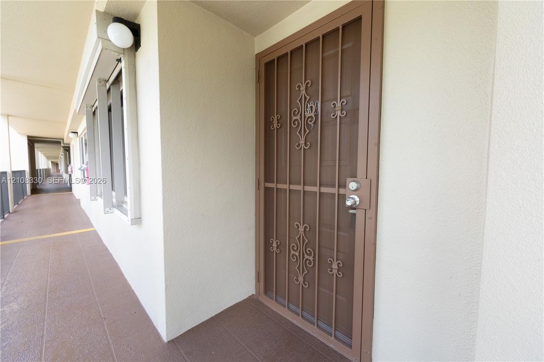 Entrance featuring a metal security screen door with decorative scrollwork and a neutral-toned stucco exterior