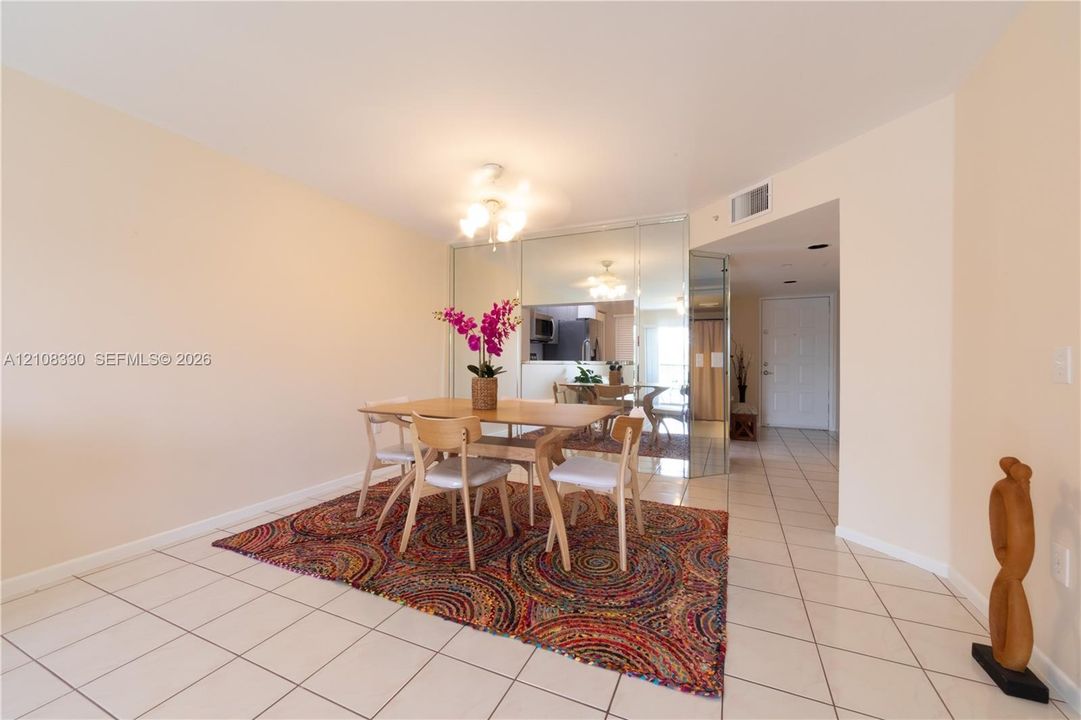 Neutral ceramic tile flooring, mirrored wall paneling, and multi-arm overhead lighting fixture