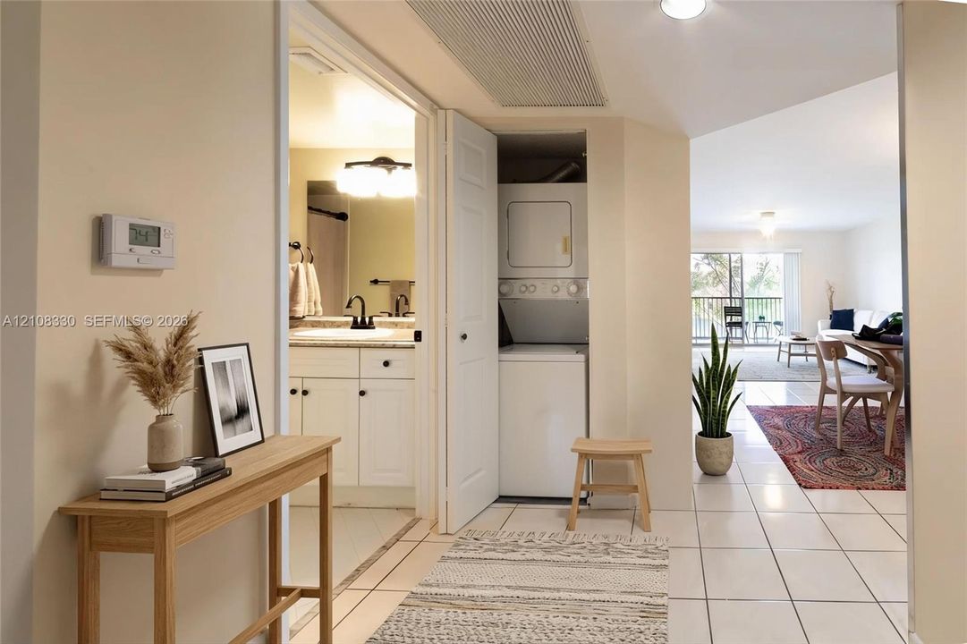 Ceramic tile flooring, built-in stacked laundry unit, bathroom vanity with stone-finish countertop, and recessed ceiling lighting