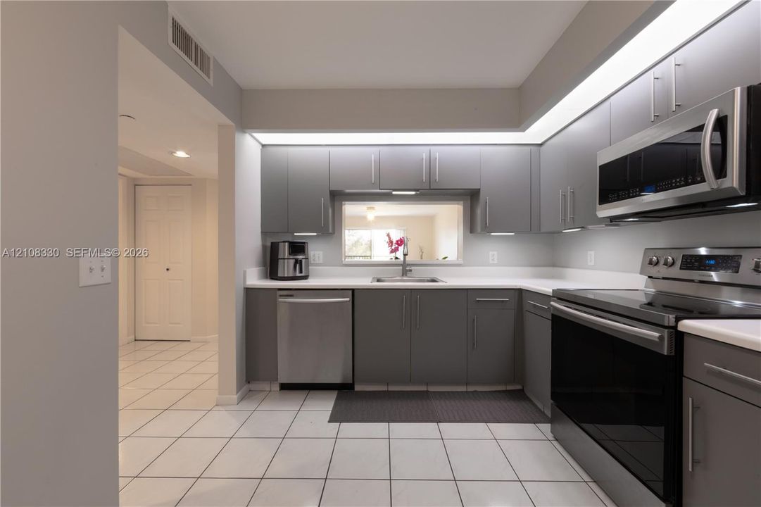Kitchen featuring grey cabinetry, white countertops, stainless steel appliances, tiled flooring, and recessed lighting