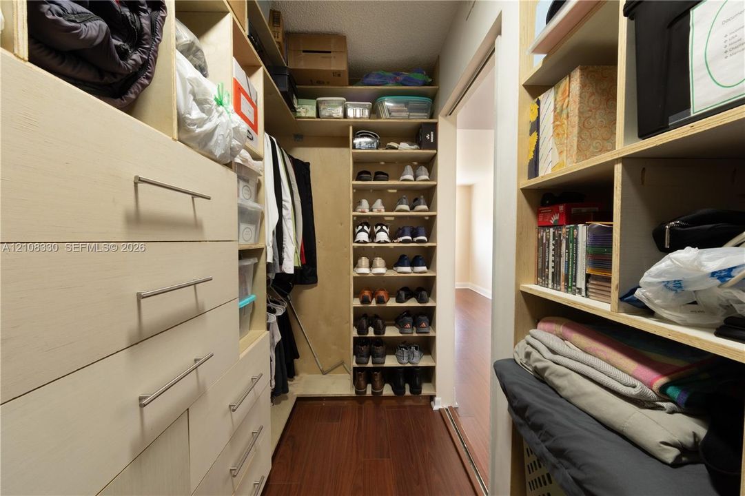 Custom walk-in closet featuring extensive built-in shelving, modular storage compartments, and integrated drawers with horizontal metal hardware