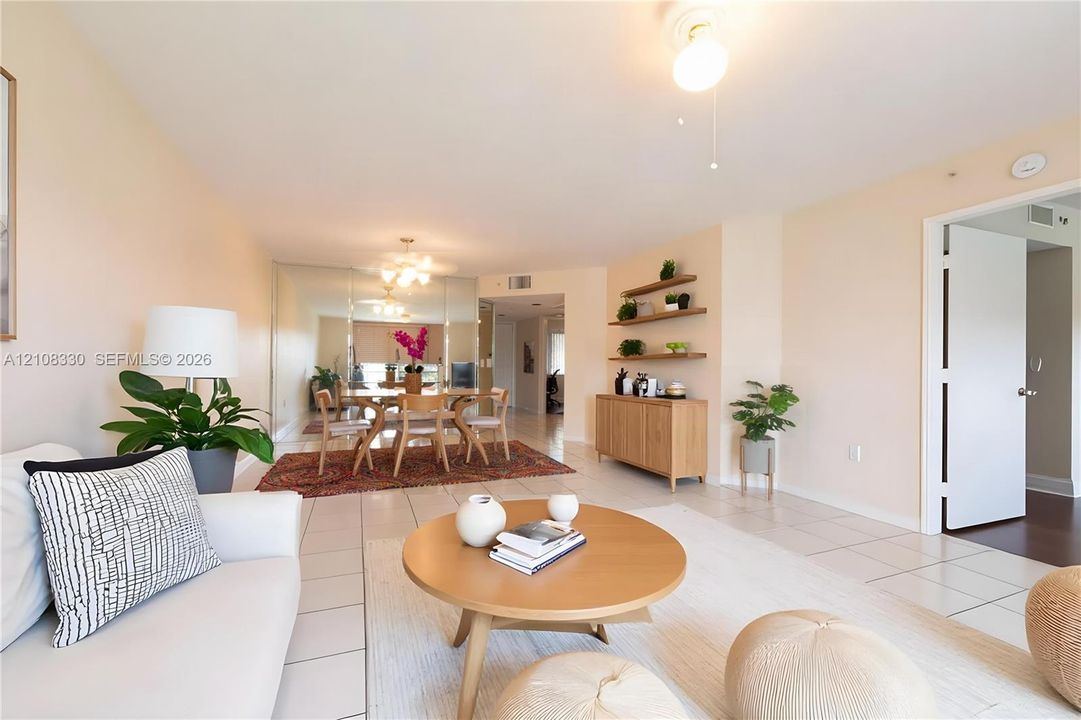 Open-concept living space featuring large-format tile flooring, mirrored wall accents, built-in wooden shelving, and a ceiling-mounted light fixture