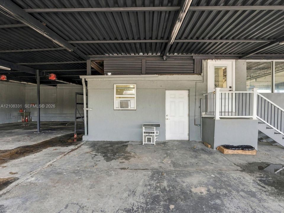 Covered outdoor area featuring a concrete surface, metal roof structure, and a raised entry platform with metal railings