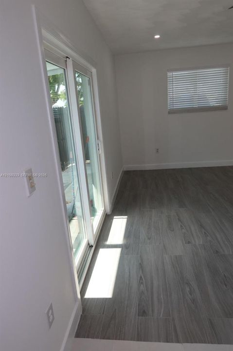 Wood-finish flooring, sliding glass door, recessed ceiling lighting, and horizontal window blinds