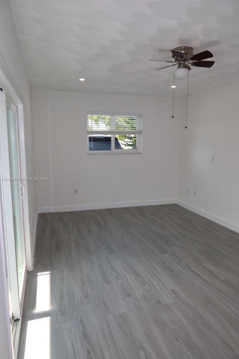 Room featuring wood-finish flooring, textured ceiling, ceiling fan, recessed lighting, and sliding glass door