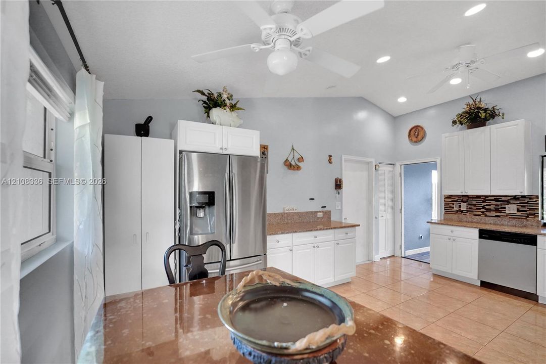 Kitchen featuring white cabinetry, stone-finish countertops, tile flooring, recessed lighting, and stainless steel appliances