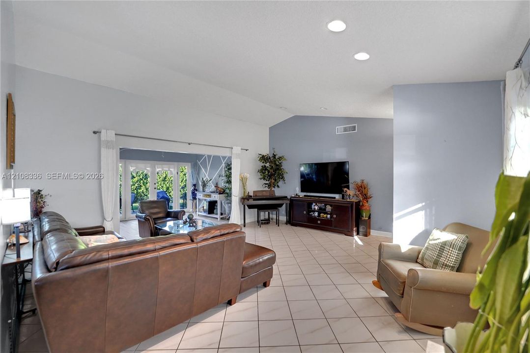 Living area featuring vaulted ceilings, recessed lighting, tile flooring, and French doors