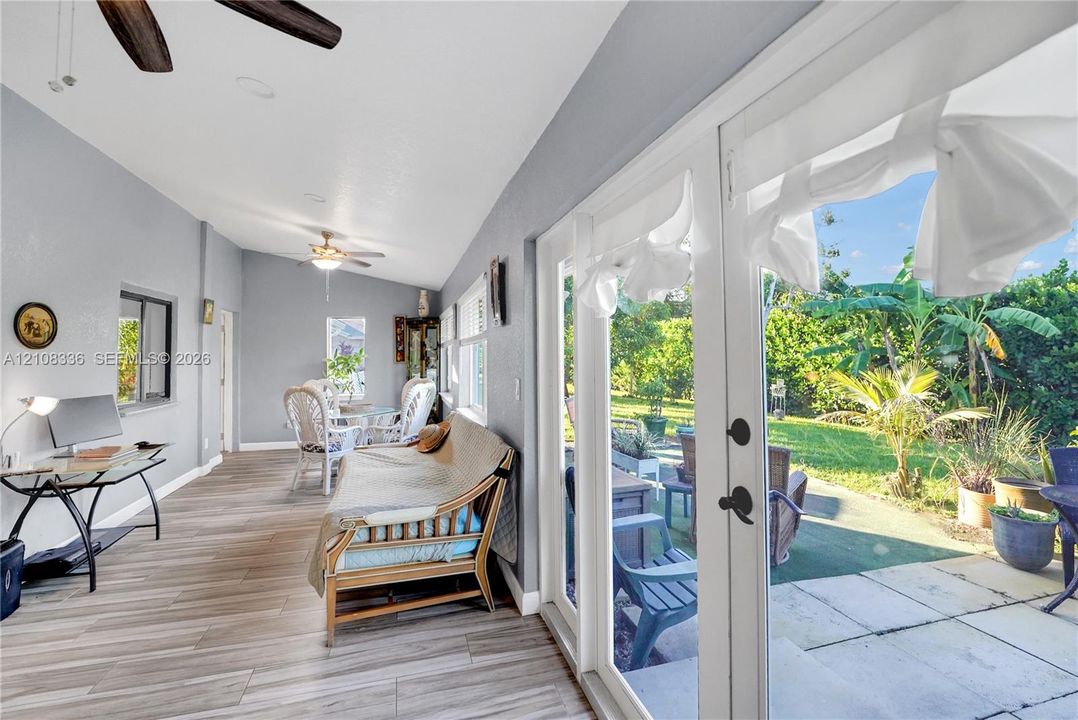 Sunroom featuring wood-finish flooring, recessed lighting, dual ceiling fans, and full-length glass panel doors opening to a paved patio