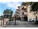 Multi-story building exterior featuring a secured gated entry, covered ground-level parking, and private balconies