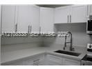 Kitchen featuring white shaker-style cabinetry, solid-surface countertops, undermount sink, gooseneck faucet, and stainless steel appliances