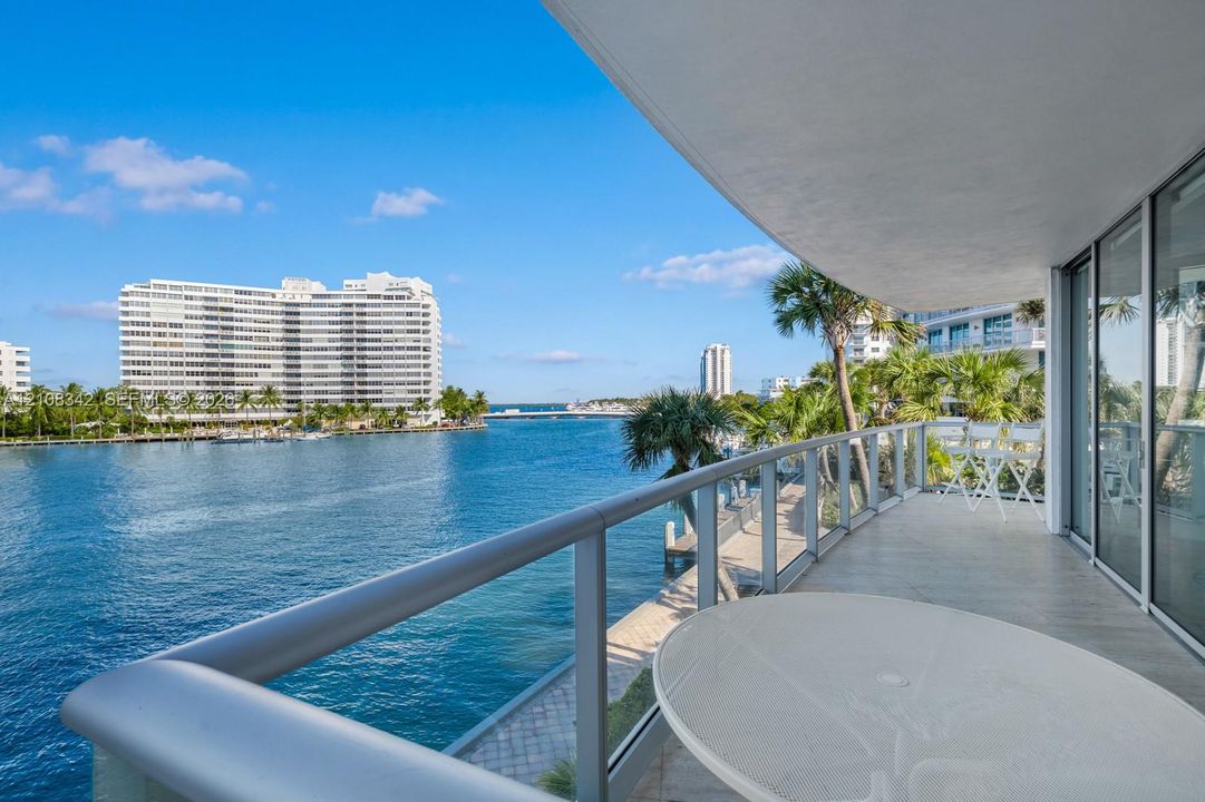 Covered balcony featuring glass railing, neutral tile flooring, and floor-to-ceiling sliding glass doors