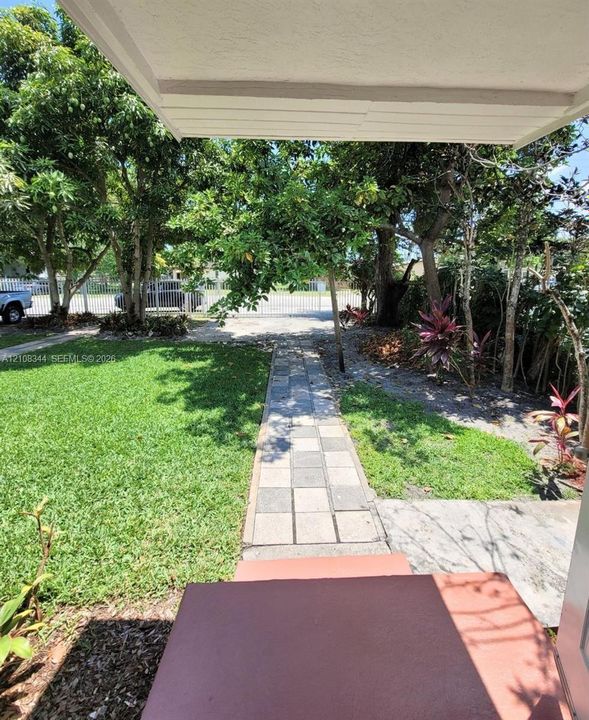 Green front yard with a paved walkway and covered entryway.