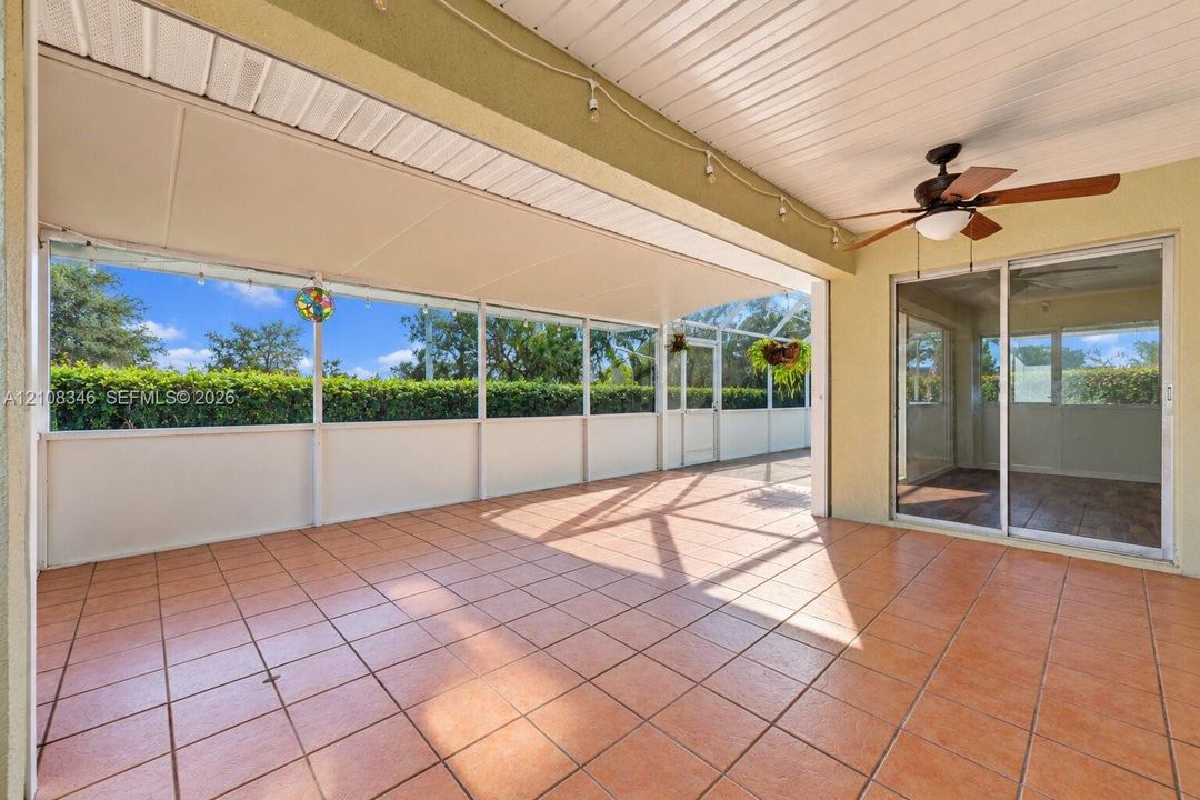 Screened-in lanai featuring ceramic tile flooring, a white paneled ceiling, a ceiling fan, and sliding glass door access