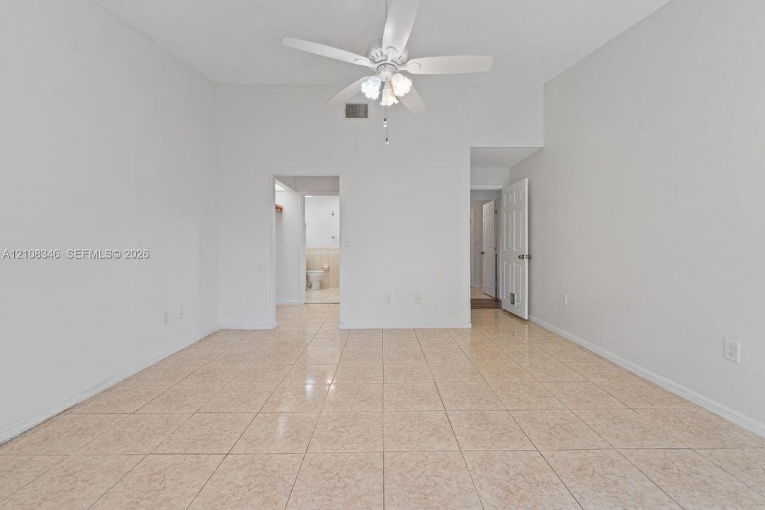 Room featuring tile flooring, vaulted ceilings, and a ceiling-mounted light fixture with fan