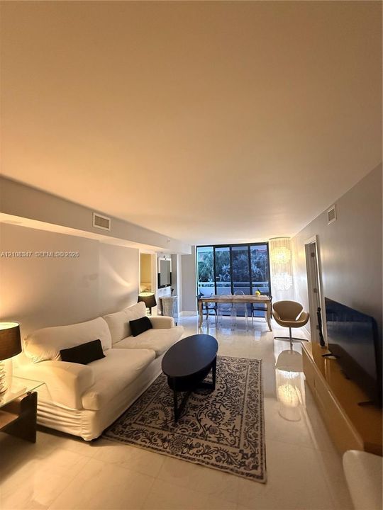 Open-concept living space featuring high-gloss tile flooring, floor-to-ceiling sliding glass doors, and recessed lighting